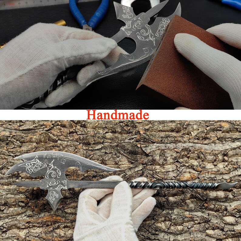 May include: A handmade metal axe with a decorative design. The axe is being sharpened on a brown sanding block.
