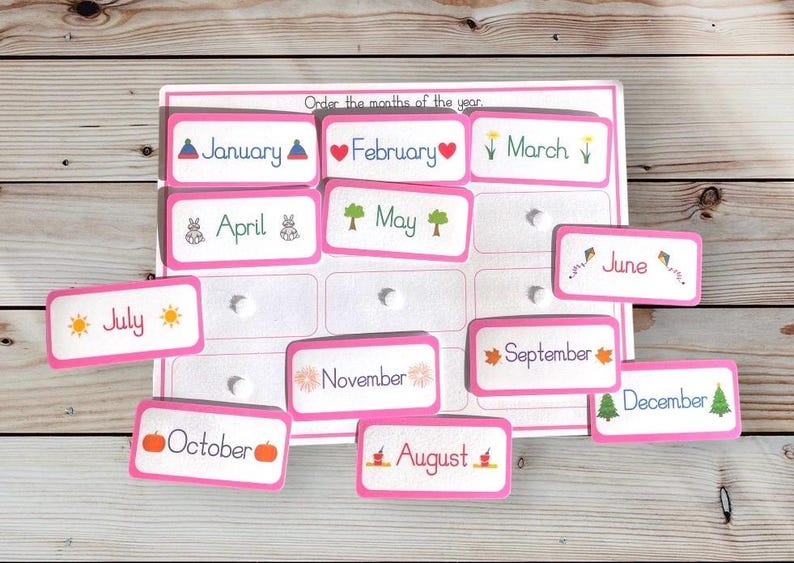 May include: Pink cards with the months of the year printed on them. Each card has a small illustration representing the month. The cards are scattered on a wooden surface. "Order the months of the year" is printed at the top of the page.