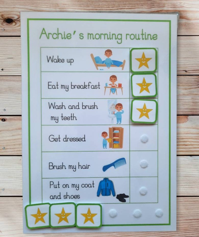 May include: A laminated morning routine chart for "Archie" with a green border. The chart includes illustrations and text for each step, such as "Wake up," "Eat my breakfast," and "Brush my hair." Star-shaped reward stickers are included.