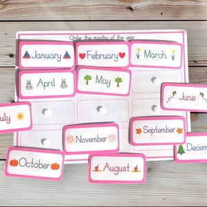 May include: Pink cards with the months of the year printed on them. Each card has a small illustration representing the month. The cards are scattered on a wooden surface. "Order the months of the year" is printed at the top of the page.