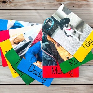 May include: A stack of colorful photo cards with names written on them. The cards feature photos of a dog, a person, and a dog in a car. The names on the cards are Tilly, Ro, Daddy, Mummy, and the dog's name.