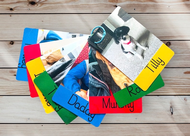 May include: A stack of colorful photo cards with names written on them. The cards feature photos of a dog, a person, and a dog in a car. The names on the cards are Tilly, Ro, Daddy, Mummy, and the dog's name.