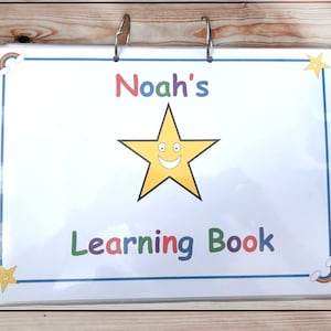 May include: A white learning book with a blue border and a yellow star with a smiley face. The book has the text "Noah's Learning Book" on the front.