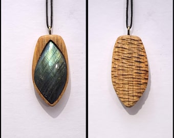 May include: A wooden pendant with a dark green and blue iridescent gemstone set in the center. The pendant is attached to a black cord.