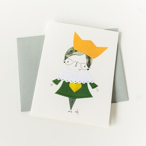 May include: A greeting card featuring a cartoon illustration of a person wearing a green dress, a white collar, and a yellow crown. The person has brown hair, glasses, and a yellow heart on their chest.