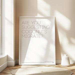 May include: A white rectangular poster in a thin white frame featuring the black text ARE YOU SUGGESTING COCONUTS MIGRATE? followed by the smaller text MONTY PYTHON AND THE HOLY GRAIL 1975 at the bottom right corner of the print.