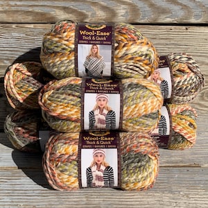 May include: A stack of colorful yarn skeins with the label "Wool-Ease Thick & Quick Stripes". The yarn is a mix of orange, yellow, green, and brown. The label features a woman wearing a scarf and hat.