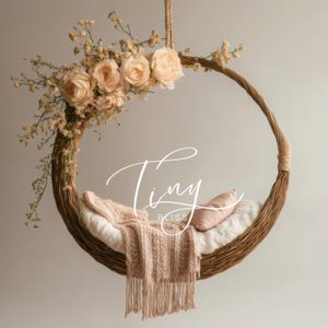 May include: A wicker swing with a white and pink blanket and a pink pillow. The swing is decorated with dried flowers, including roses and baby's breath. The text "Tiny Bliss Photography" is written on the swing.