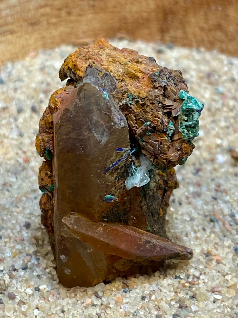 May include: A cluster of brown, green, and clear crystals with a rough, textured surface. The crystals are arranged in a random pattern and appear to be naturally formed.