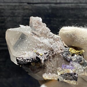 May include: A cluster of clear quartz crystals with a variety of other minerals, including pyrite, fluorite, and chalcopyrite. The crystals are arranged in a natural, organic pattern, and the overall effect is one of beauty and wonder.