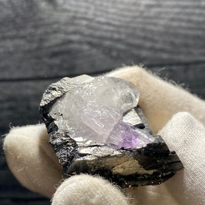 May include: A cluster of amethyst crystals with a purple hue, embedded in a matrix of black and silver pyrite. The crystals are translucent and have a glassy luster.