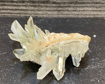 May include: A cluster of clear quartz crystals with a green hue, forming a unique and intricate shape. The crystals are arranged in a natural, organic pattern, creating a visually appealing and interesting piece.