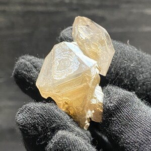 May include: A cluster of two clear quartz crystals with a light brown hue. The crystals are faceted and have a natural, rough texture.