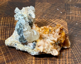 May include: A cluster of clear and brown crystals on a rock. The crystals are arranged in a natural, organic pattern.