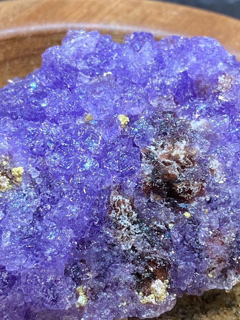Puede incluir: Primer plano de un c&uacute;mulo de cristal de amatista p&uacute;rpura con una superficie rugosa y texturizada. El cristal tiene un color p&uacute;rpura intenso con un ligero brillo iridiscente.