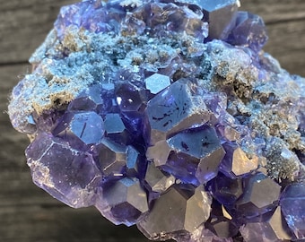 May include: A cluster of deep purple fluorite crystals with a rough, natural texture. The crystals are clustered together in a dense formation, creating a visually interesting and unique piece.