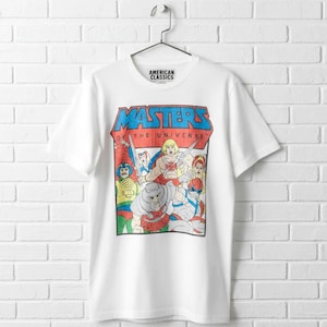 May include: White t-shirt featuring a colorful graphic of characters from the Masters of the Universe cartoon series. The shirt has the text "MASTERS OF THE UNIVERSE" in a bold, retro font. The top of the shirt has the text "AMERICAN CLASSICS".