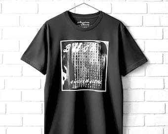 May include: A black short-sleeve t-shirt featuring a white square graphic on the chest. The graphic displays a textured, grid-like pattern with the text "BUSH" at the top and "sixteen stone" at the bottom. The shirt has a crew neckline and is displayed on a hanger.