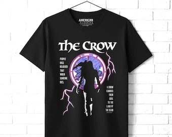 May include: A black short-sleeve t-shirt featuring a graphic of a silhouette standing before a circular purple and white window. The text reads: The Crow, People once believed that when someone dies, a crow carries their soul to the land of the dead.