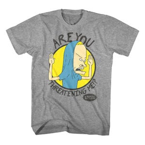 May include: A gray t-shirt featuring a cartoon character inside a yellow circle. The character is wearing a blue hood and has arms raised. The text above reads "ARE YOU", and below, "THREATENING ME?". The shirt also has the text "BEAVIS BUTT-HEAD".