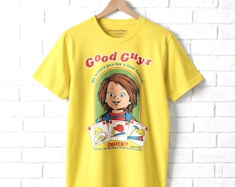 May include: A bright yellow short-sleeve t-shirt featuring a graphic of the character Chucky. The print includes the text Good Guys, He wants you for a best friend, CHUCKY, and Collect all the Good Guys accessories, along with small illustrations.