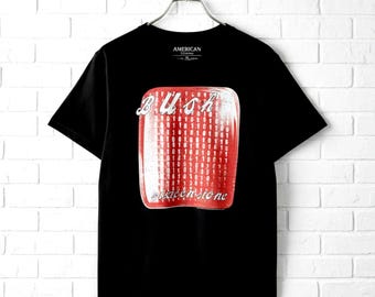 May include: A black short-sleeve t-shirt featuring a central red rectangular graphic with a binary code pattern. The text "BUSH" appears in white above the rectangle, and the text "sixteen stone" is printed in white script below the graphic.