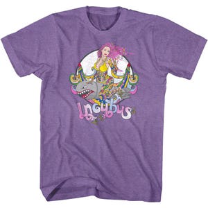 May include: Purple t-shirt featuring a graphic of a woman with pink hair riding a shark-shaped bomb. The design includes the word "Incubus" in a stylized font, with colorful accents.