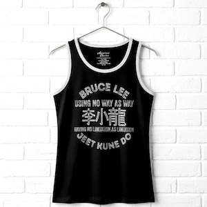 May include: A black tank top with white trim around the neckline and armholes. The front features a distressed white graphic with the text Bruce Lee, Using No Way As Way, the Chinese characters 李小龍, Having No Limitation As Limitation, and Jeet Kune Do.
