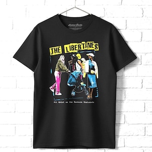 May include: Black t-shirt featuring a graphic of three figures with the text "THE LIBERTINES" in a yellow rectangle. Below the graphic is the text "All Quiet on the Eastern Esplanade". The shirt is hanging on a metal hanger.