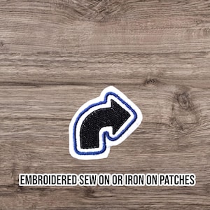 May include: Embroidered patch with a black arrow, blue outline, and white border. Designed for sewing or ironing onto fabric. The text "EMBROIDERED SEW ON OR IRON ON PATCHES" is displayed at the bottom of the image.