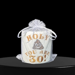 May include: A roll of white toilet paper with gold embroidered text reading "HOLY YOU ARE 30!" and a poop emoji. The toilet paper is presented in a sheer white gift bag, tied with a ribbon.