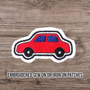 May include: Embroidered patch of a red car with blue windows and black wheels, outlined in white and black. The text "EMBROIDERED SEW ON OR IRON ON PATCHES" is below the car.