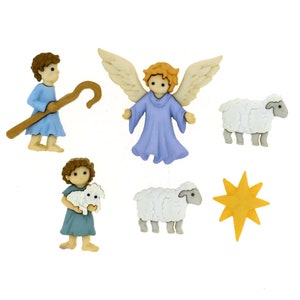 May include: A set of six plastic buttons featuring a nativity scene. The buttons depict a shepherd with a staff, an angel with wings, two white sheep, a yellow star, and a shepherd holding a lamb.