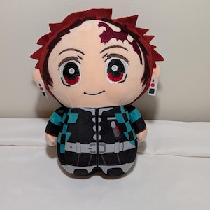 May include: Plush doll of a character with red hair and eyes, wearing a black and teal checkered outfit. The doll has a smiling face and is approximately 20 cm tall.