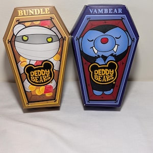 May include: Two coffin-shaped boxes labeled Deddy Bears. The left box is tan, labeled Bundle, and features a mummy bear with yellow eyes and gold coins. The right box is purple, labeled Vambear, and features a blue vampire bear with fangs.
