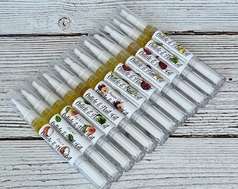 May include: A close-up of a stack of clear plastic tubes containing cuticle and nail oil. The tubes are labeled with different fruit scents, including apricot, mint, coconut, and passion fruit.