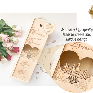 May include: A wooden wine bottle box with a laser-cut design of a couple standing on a bridge. The box is decorated with the words "Congratulations on your engagement" and "S & T 2023".