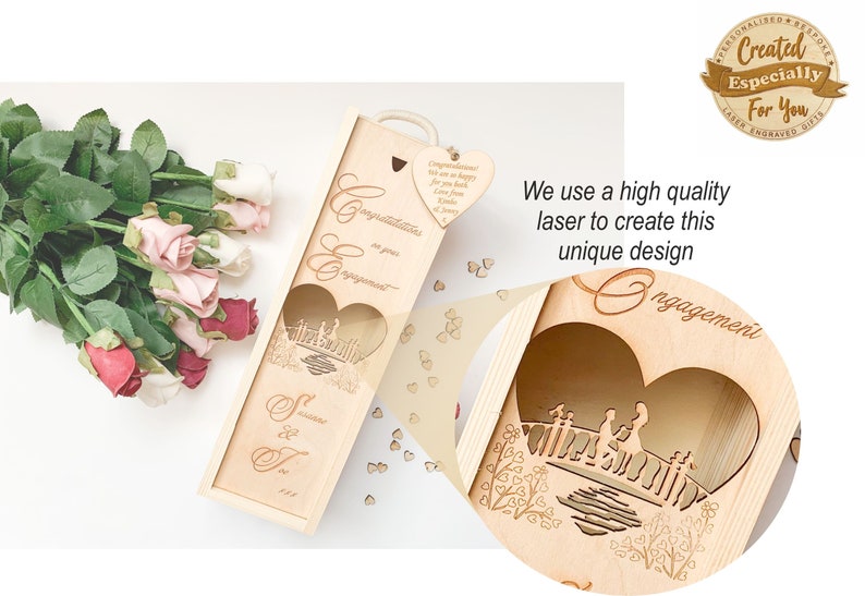 May include: A wooden wine bottle box with a laser-cut design of a couple standing on a bridge. The box is decorated with the words "Congratulations on your engagement" and "S & T 2023".