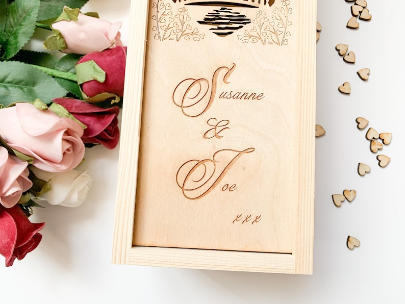 May include: A wooden box with a personalised inscription that reads "Susanne & Joe xxx". The box is decorated with a floral design and a heart motif.