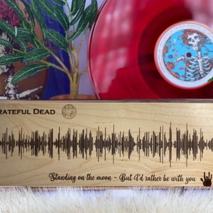 May include: A wooden plaque with the text "GRATEFUL DEAD" and a sound wave graphic. The text "Standing on the moon - But I'd rather be with you" is also engraved on the plaque.