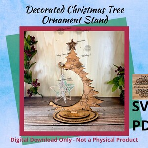 May include: A laser cut wooden Christmas tree ornament stand with a decorative design. The stand is shaped like a Christmas tree with a circular base. The stand is designed to hold Christmas ornaments.