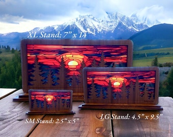 May include: Three wooden stands with a sunset scene cut out. The stands are labelled "XL Stand: 7" x 14", "LG Stand: 4.5" x 9.5", and "SM Stand: 2.5" x 5".