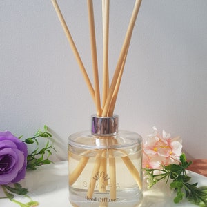 May include: A clear glass bottle with a silver lid and wooden sticks, filled with a light yellow liquid. The bottle has a label that reads "Siyara Reed Diffuser".