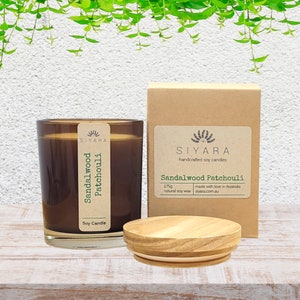 May include: A brown glass soy candle with a wooden lid. The candle is labelled "Sandalwood Patchouli" and is 175g. The candle is made with natural soy wax and is handcrafted in Australia.