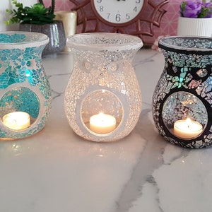 May include: Three mosaic glass oil diffusers with teal, white, and black designs. Each diffuser has a round opening for a tea light candle.