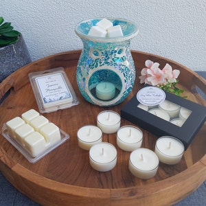 May include: A wooden tray with a teal mosaic wax warmer, a box of tea light candles, a pack of wax melts labelled "Japanese Honeysuckle", and a pack of six wax melts.