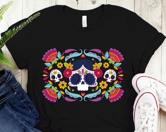 May include: Black t-shirt with a colorful Day of the Dead sugar skull design. The skull is surrounded by flowers and swirls.