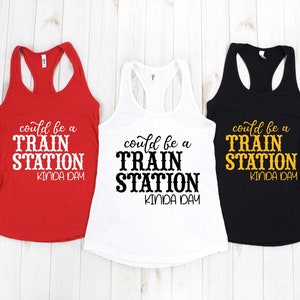 May include: Three tank tops with the text "could be a train station kinda day" printed on them. The tank tops are red, white, and black.
