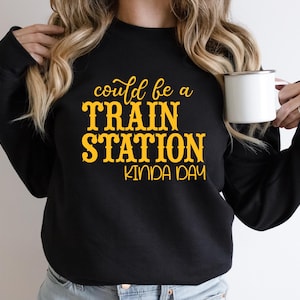May include: Black sweatshirt with the text "could be a TRAIN STATION kinda day" in yellow.