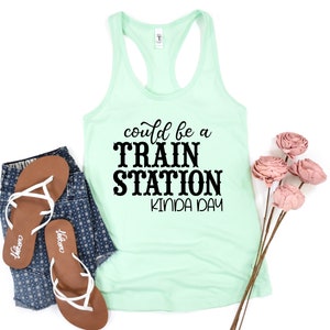 May include: A light green tank top with the text "could be a TRAIN STATION kinda day" in black lettering.